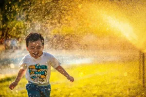 child running through hose shower so feel the joy with Rachel Bamber Brighter Thinking