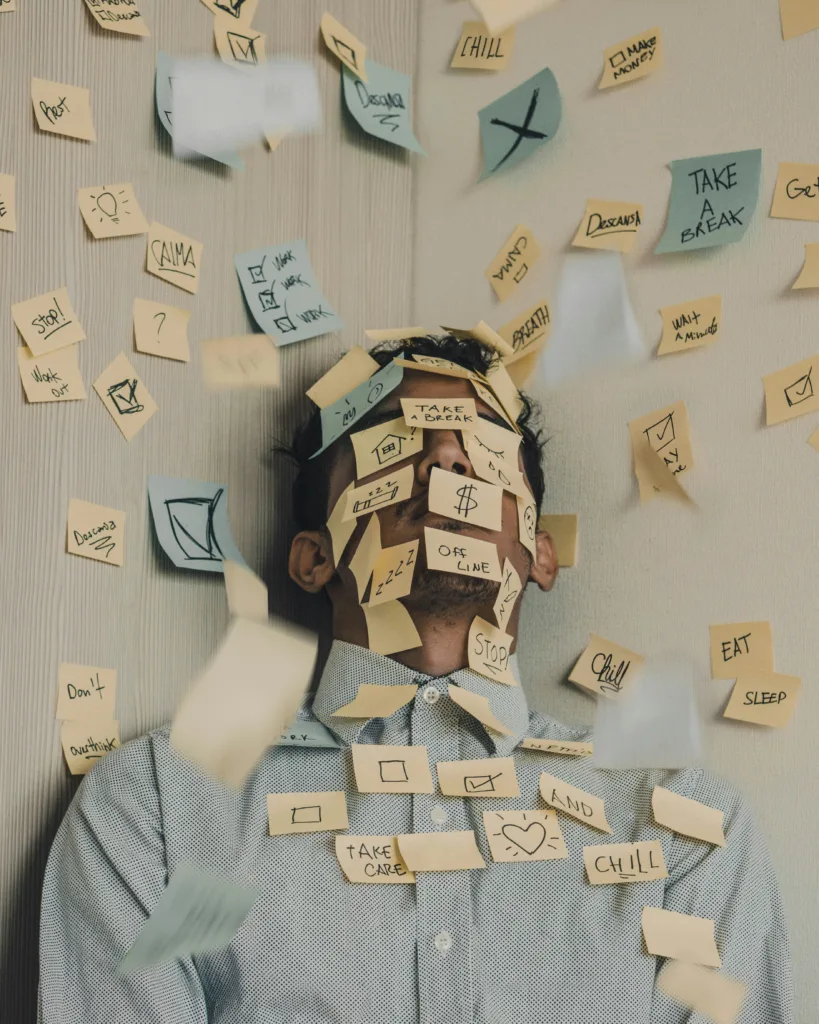Man overwhelmed with Post-It notes all over his face. He needs Rachel Bamber's Executive Coaching!
